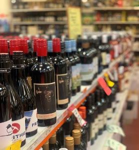Red wine bottles lined up on the shelves at Amato's